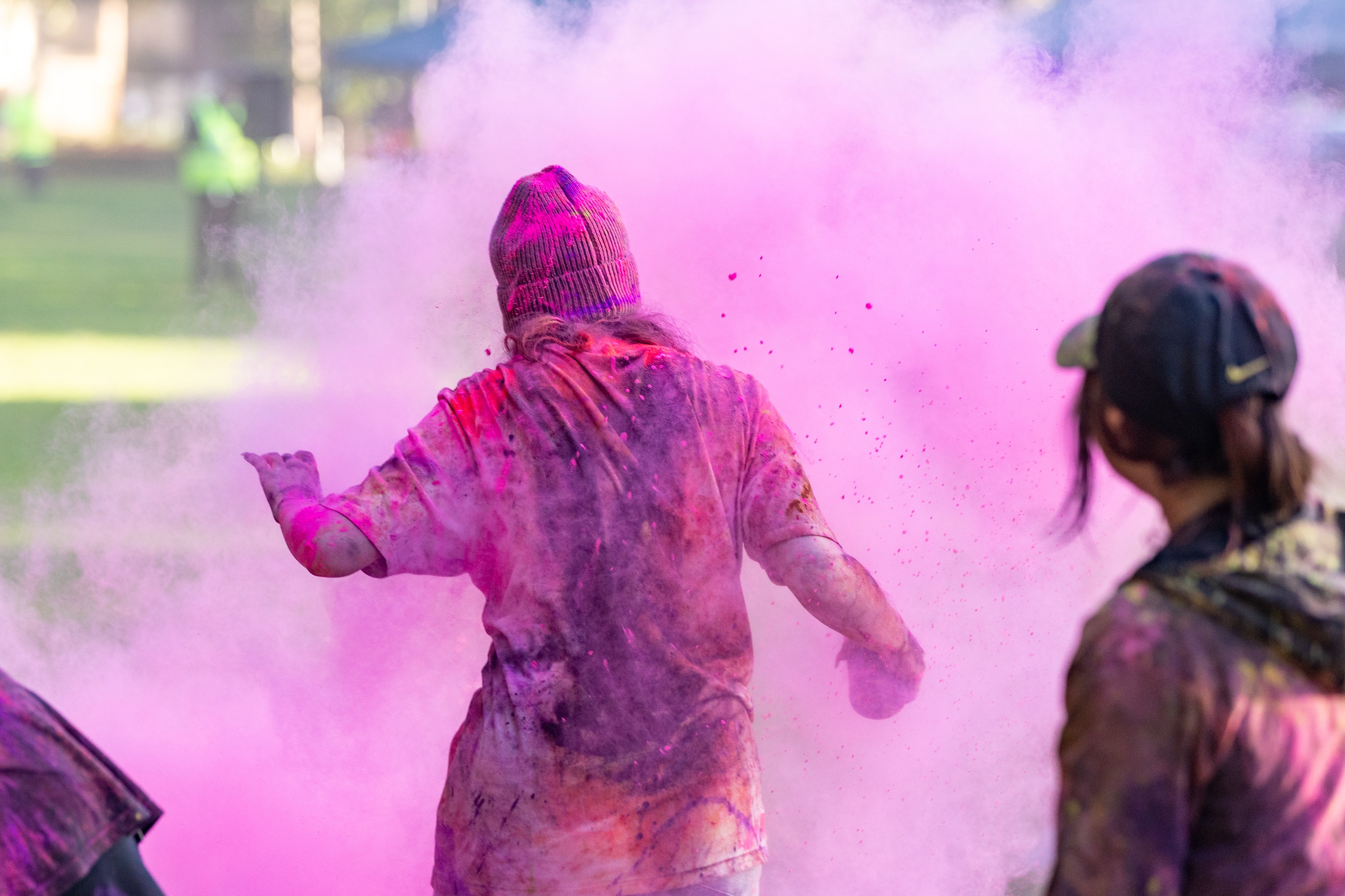 A young person covered in pink Holi powder at Colourfest.