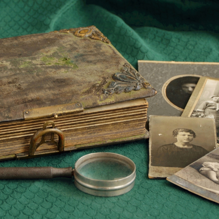 A spread of an old diary, some faded photos and a magnifying glass.