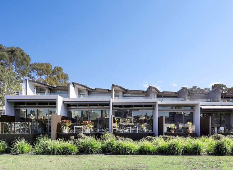 A row of modern townhouses, with a green lawn in front of them