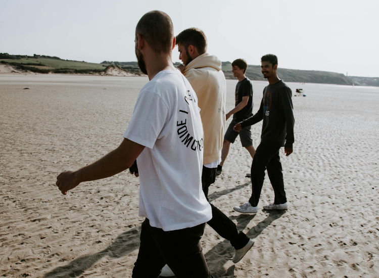 A group of four men strolling on a beach