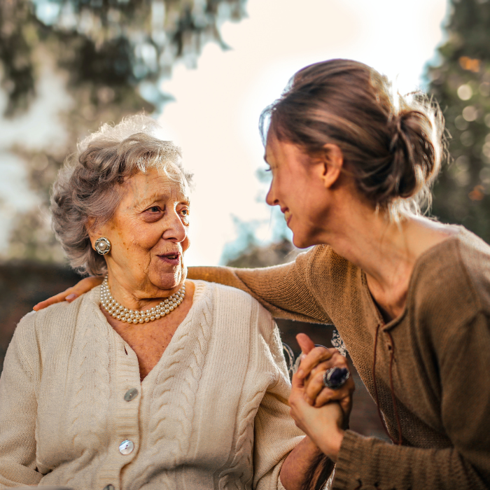 Photo of an elderly woman holding the hand of a younger woman.