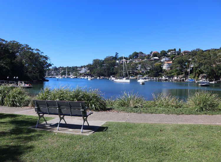 A park bench in a park facing Sydney Harbour