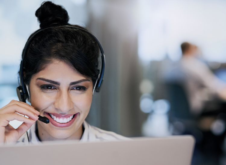 Woman wearing headset phone looking at computer smiling