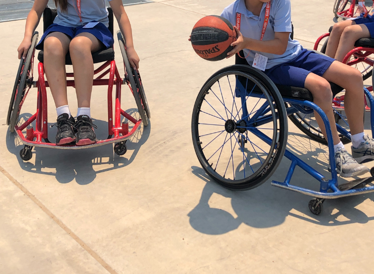 A photo of three children playing wheelchair basketball