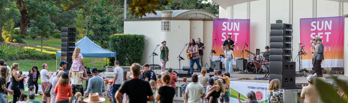 Crowd facing stage with a band performing. Banners that read &#039;sunset series&#039; are on either side